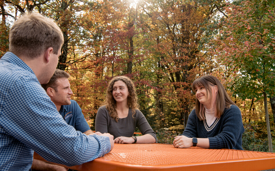 4 people sitting at a table outside