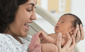 Woman holding a baby thanks to Raydiant oximetry fetal monitoring device