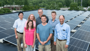 Six people posing with solar panels