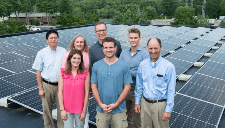 Six people posing with solar panels
