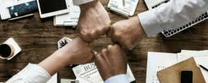 Four fists "bumping" over desk