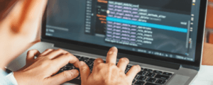 Hands over a laptop keyboard with a blurred screen in the background