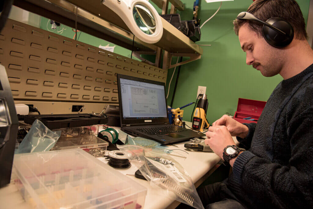 Man working at a electronics test bench, wearing headphones