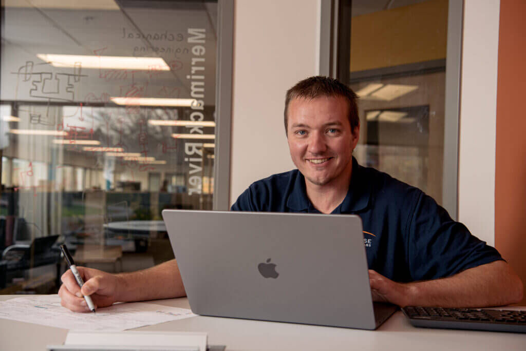 Man smiling from behind laptop